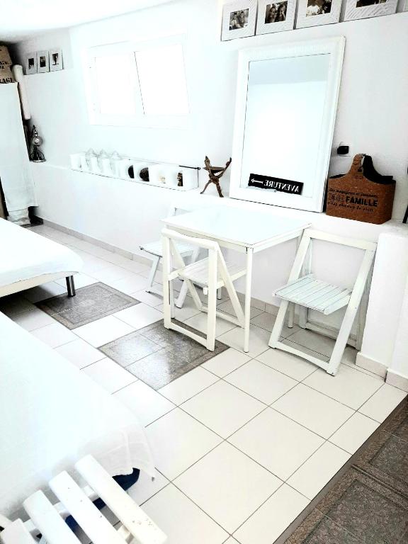 a white tiled room with a white table and chairs at Apartments House of Art in Nin