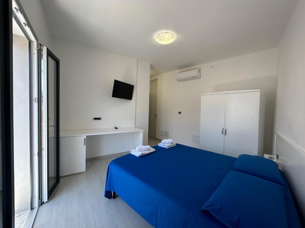 1 dormitorio con 1 cama azul y TV en Domu Dina Affittacamere 4, en Tertenìa