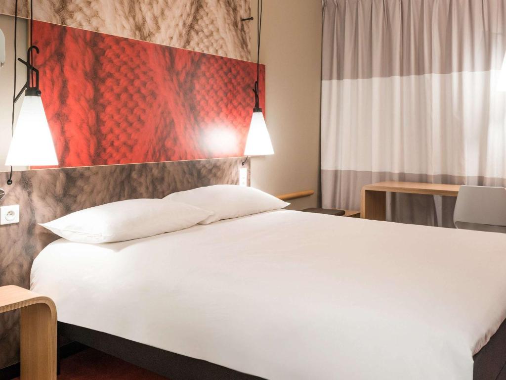 فندق إيبيس لايبزيغ سيتي في لايبزيغ: غرفة نوم بسرير ابيض كبير وعلم