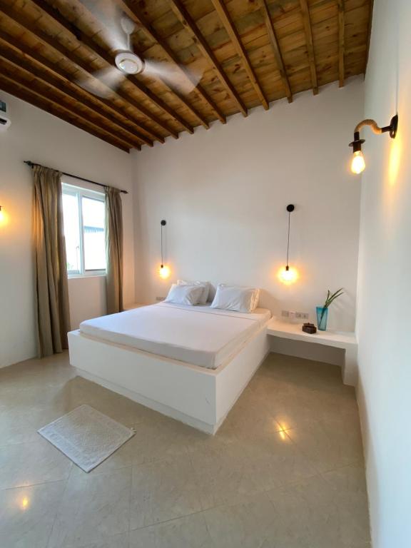 a white bedroom with a large bed and a window at Cactus lodge Zanzibar in Nungwi