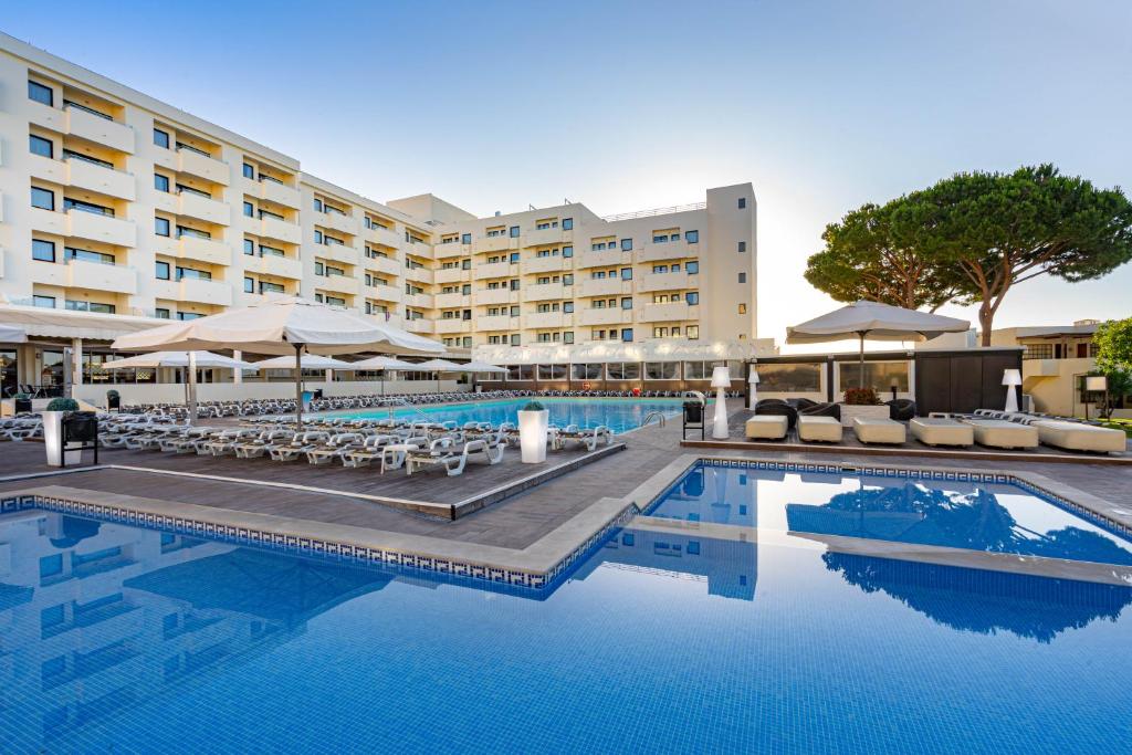アルブフェイラにあるAlbufeira Sol Hotel & Spaのホテルのスイミングプール(椅子付)とホテルを提供しています。