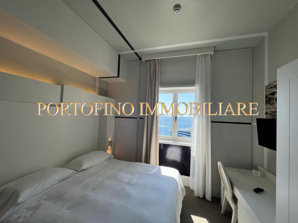 een slaapkamer met een wit bed en een raam bij PORTOFINO SUITE VISTA MARE CON SPIAGGIA PRIVATA in Portofino