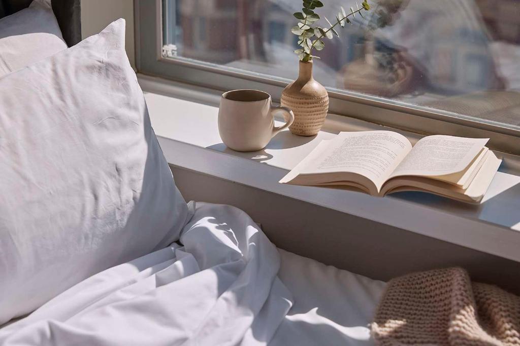 an open book on a table next to a window with a coffee cup at Pensione Hotel Perth in Perth