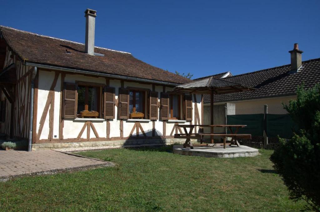 ein Haus mit einem Picknicktisch und einem Sonnenschirm in der Unterkunft Au logis des lacs in Piney