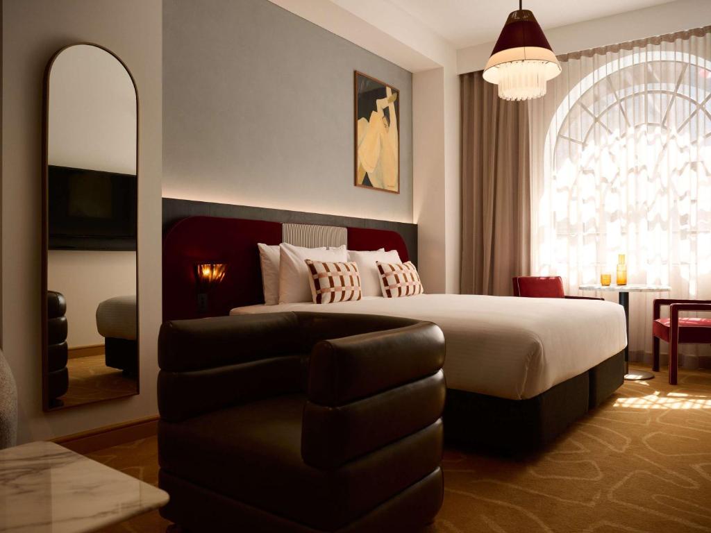 una camera con letto, specchio e divano di Hotel Morris Sydney, Handwritten Collection a Sydney