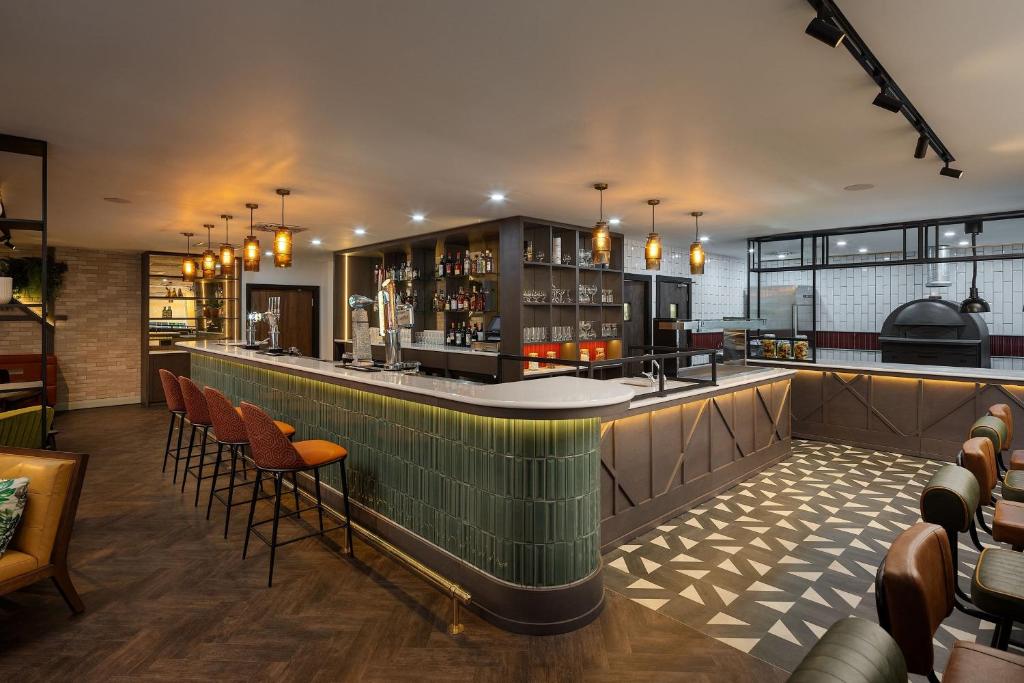 un bar dans un restaurant avec des chaises orange dans l'établissement Four Points by Sheraton Edinburgh, à Édimbourg