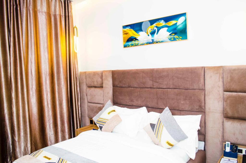 um quarto com uma cama com lençóis brancos e almofadas em Ozinny Signatures Hotel em Jidu