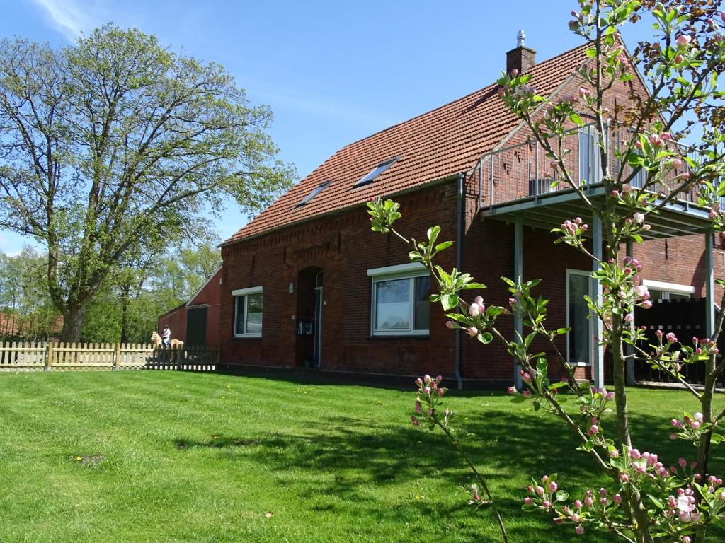 une maison en briques rouges avec une cour verdoyante dans l'établissement Ferienhof Ostarle, à Arle