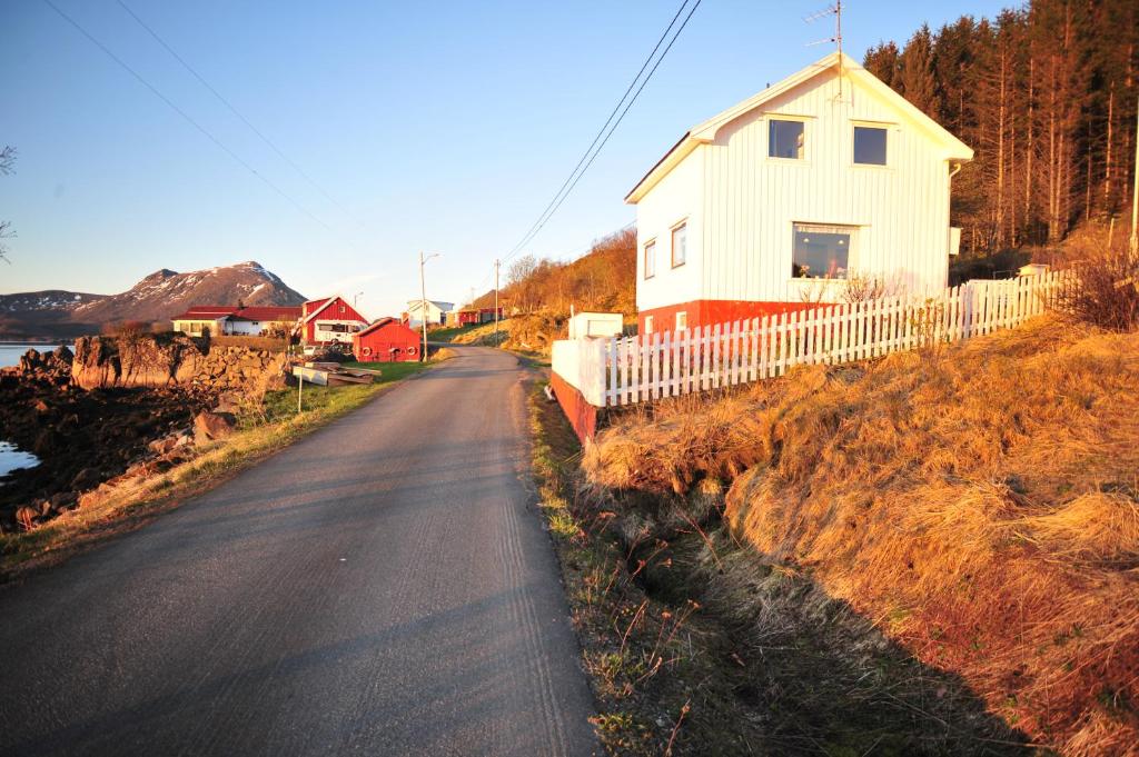 a house on the side of a road next to a fence at Fredelig med naturskjønn omgivelse, midt i Lofoten in Jerstad