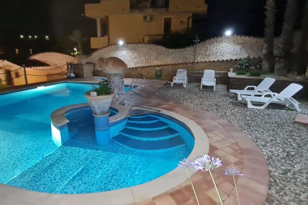 a swimming pool in the middle of a resort at night at Victoria House in Mascalucia