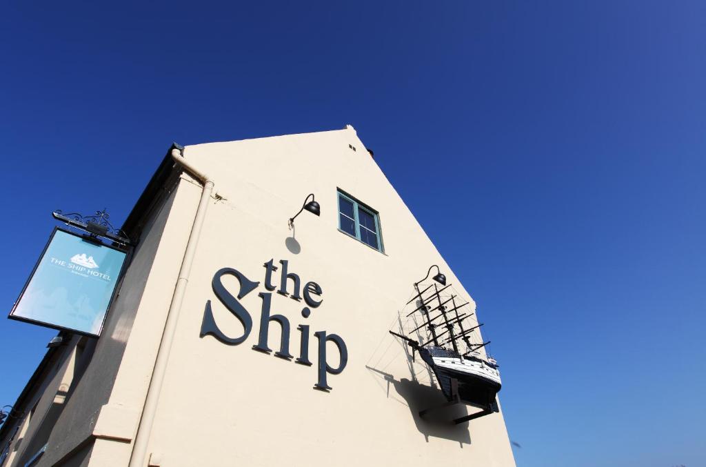 a building with a sign on the side of it at The Ship Hotel in Brancaster