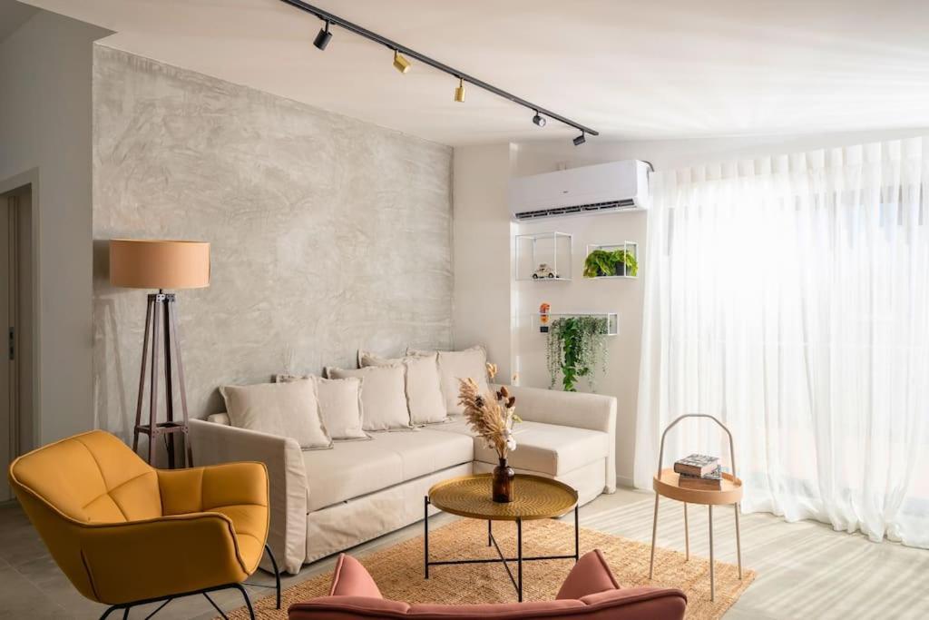 ein Wohnzimmer mit einer weißen Couch und einem gelben Stuhl in der Unterkunft Romano Neve Tzedek Penthouse in Tel Aviv