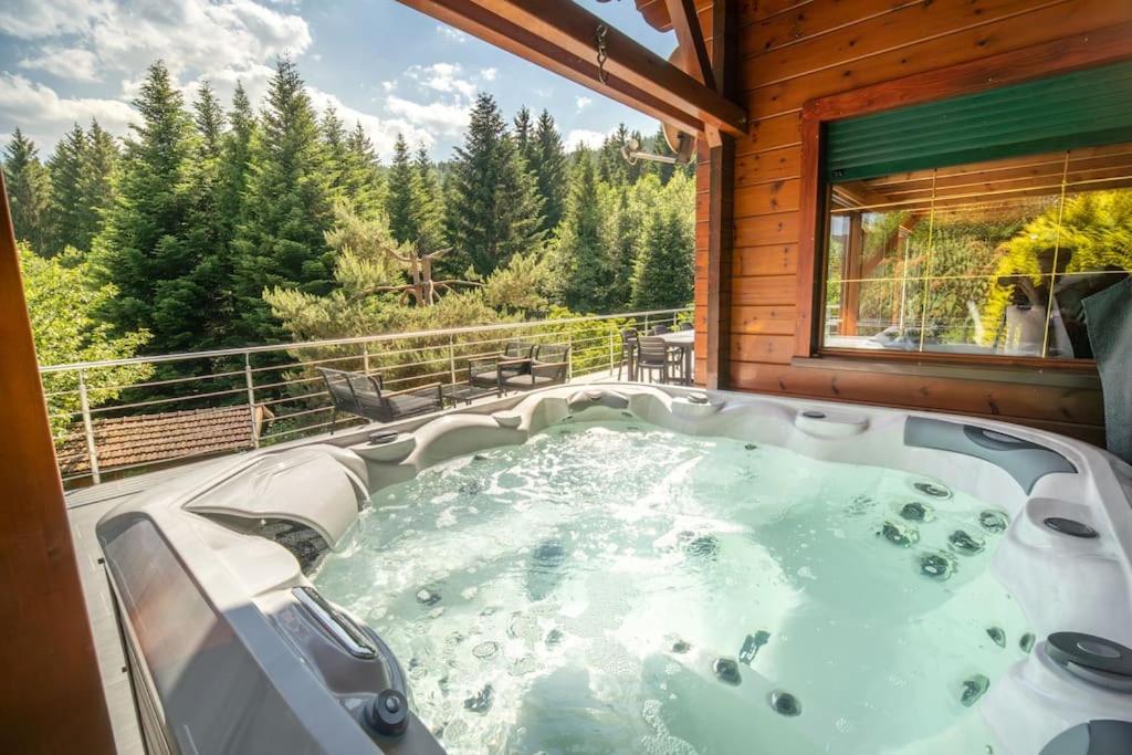 a jacuzzi tub on the balcony of a cabin at Le Chant du Ruisseau SPA - Sauna in Le Tholy
