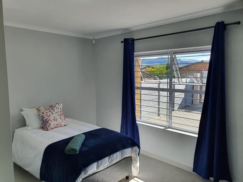 um quarto com uma cama com cortinas azuis e uma janela em Stellenbosch Idasvalley Gem em Stellenbosch