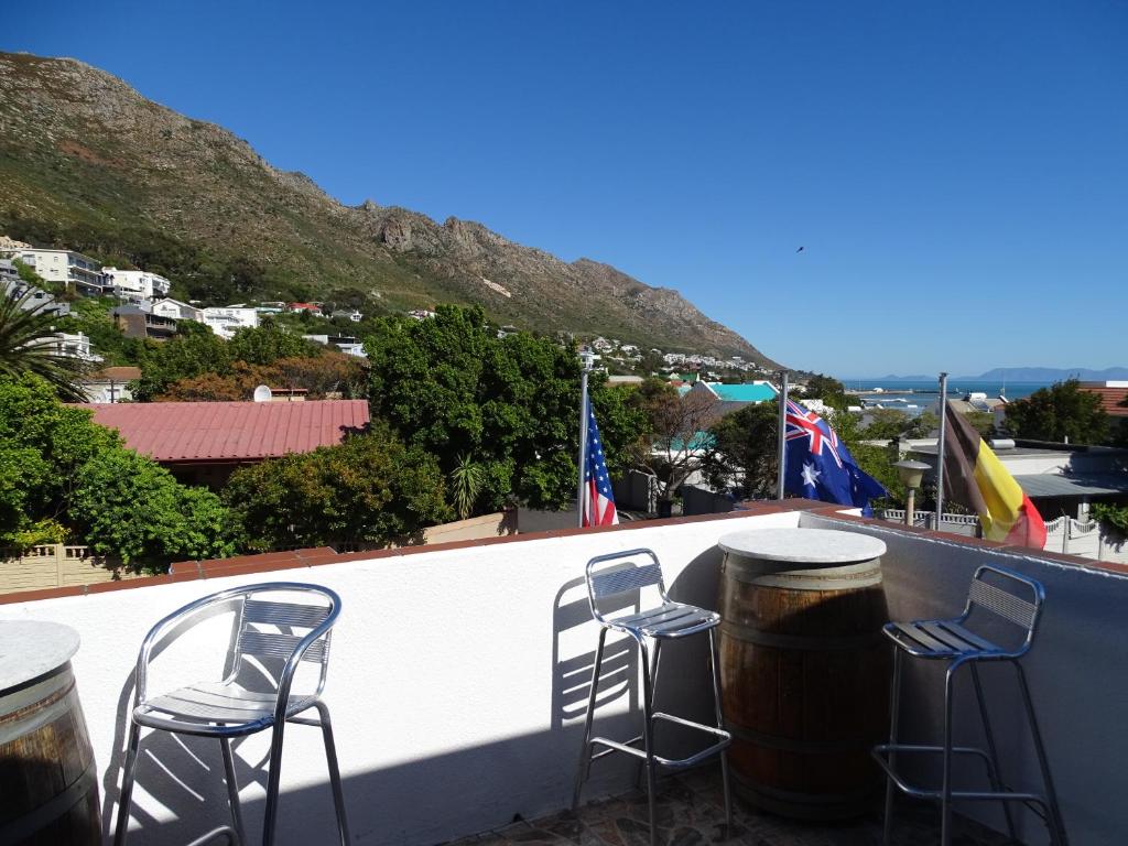 un gruppo di sgabelli seduti su un balcone con bandiere di Big Skies Guesthouse a Gordonʼs Bay