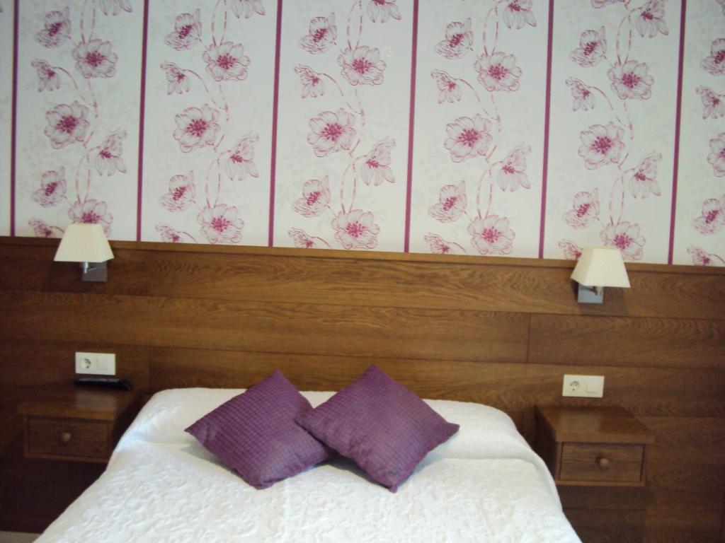 sypialnia z łóżkiem z 2 fioletowymi poduszkami w obiekcie Casa Fuentes w mieście Poio