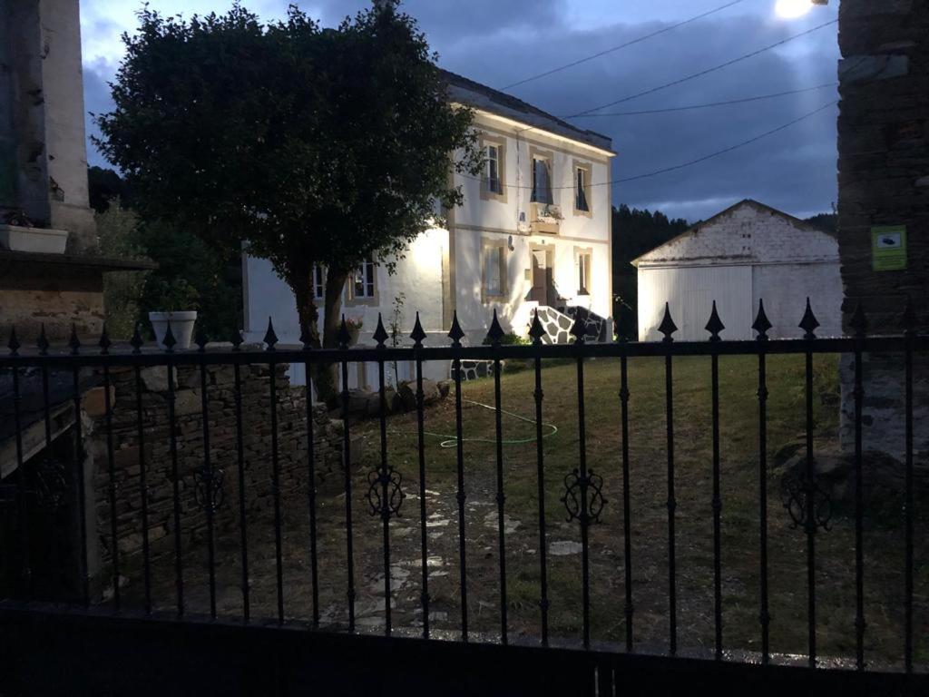 una cerca negra frente a una casa blanca en Casa de Campo Pumarada de Oirín en Foz