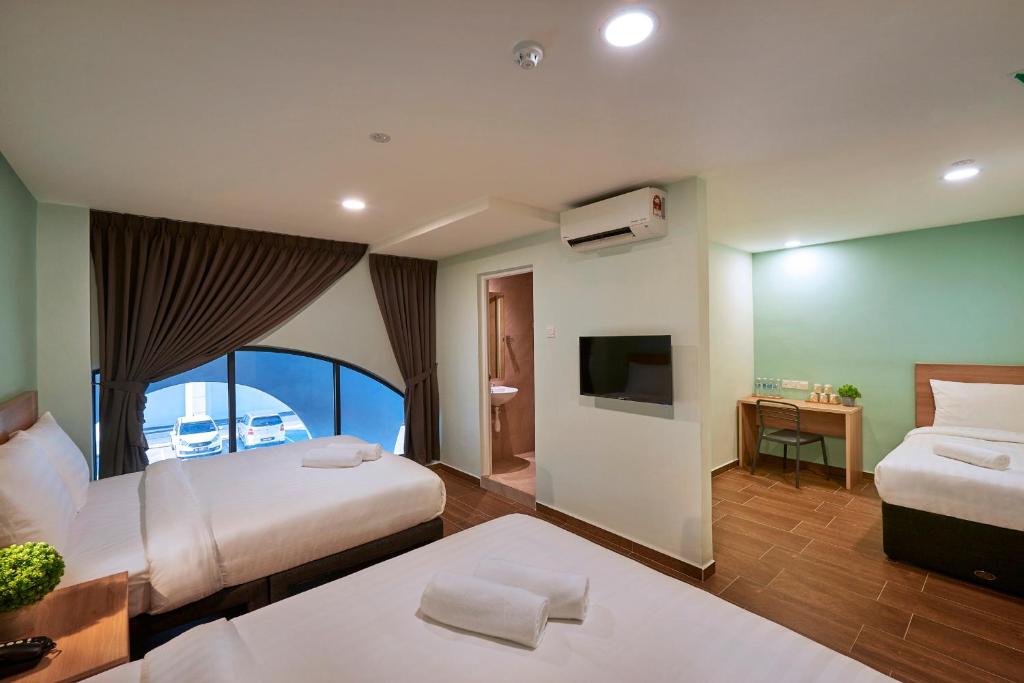 a hotel room with two beds and a television at ZONE Hotels, Eco Grandeur in Bandar Puncak Alam