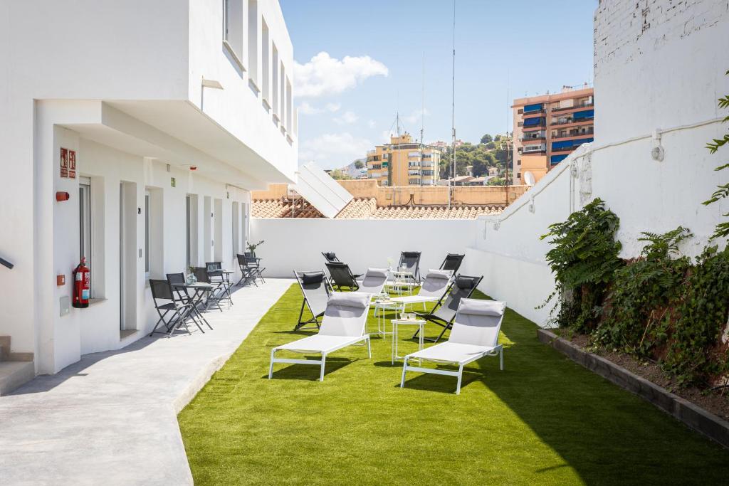 un patio con sillas, mesa y césped en Apartamentos LA PELUSA, en Málaga