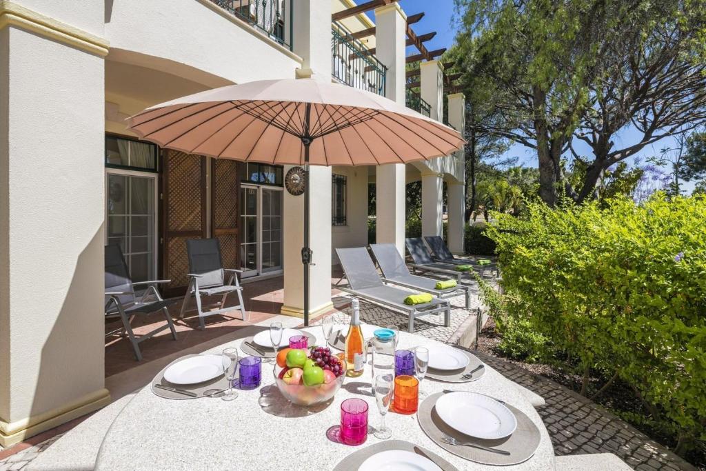 a table with a bowl of fruit and an umbrella at Sera - Luxury 3 bedroom apartment with pool, golf,beach in Ludo