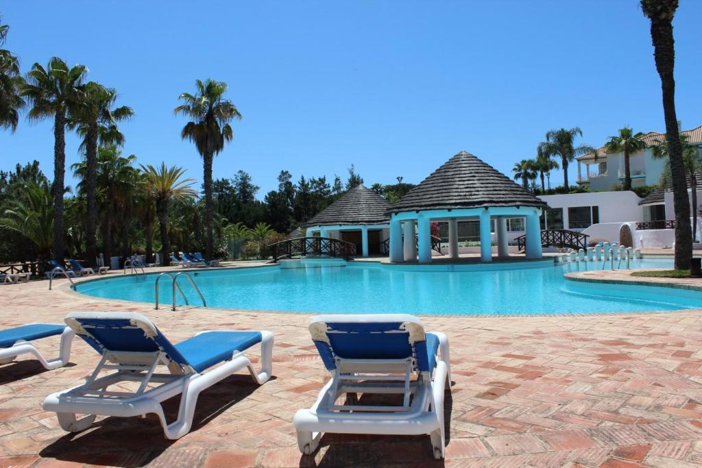 una piscina con due sedie a sdraio e un gazebo di Tulio 2 Bedroom Luxury Apartment located in Encosta Do Lago a Quinta do Lago