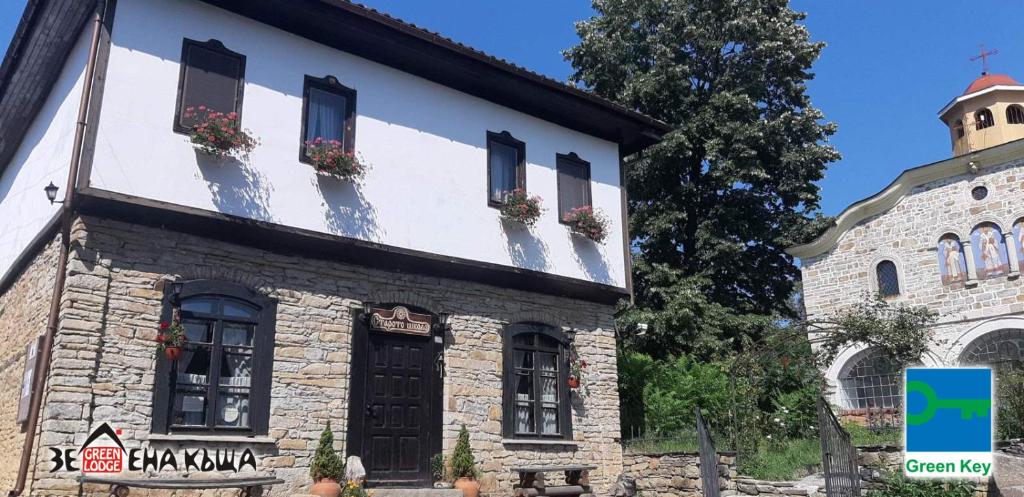 an old stone building with windows and a church at Staroto Shkolo House - rooms for guests in Bozhentsi