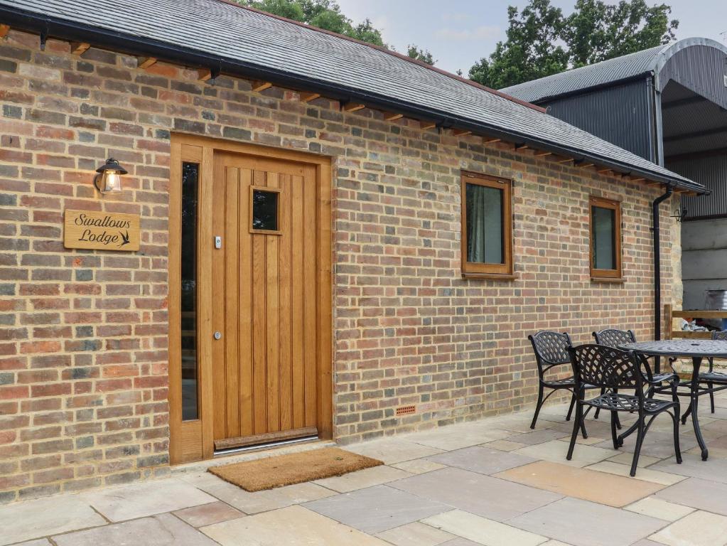 a brick building with a wooden door and a table at Swallows Lodge in Edenbridge