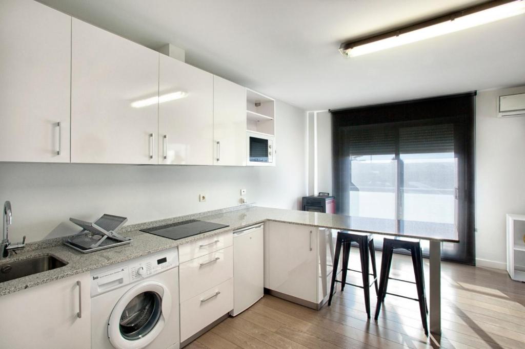 eine weiße Küche mit einer Waschmaschine und einem Tisch in der Unterkunft Habitur Experiences 2 in Olite