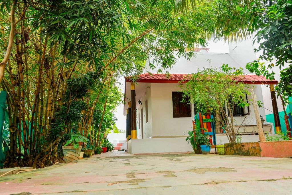 een klein wit huis met bomen ervoor bij Mahabs homestay Villa in Mahabalipuram
