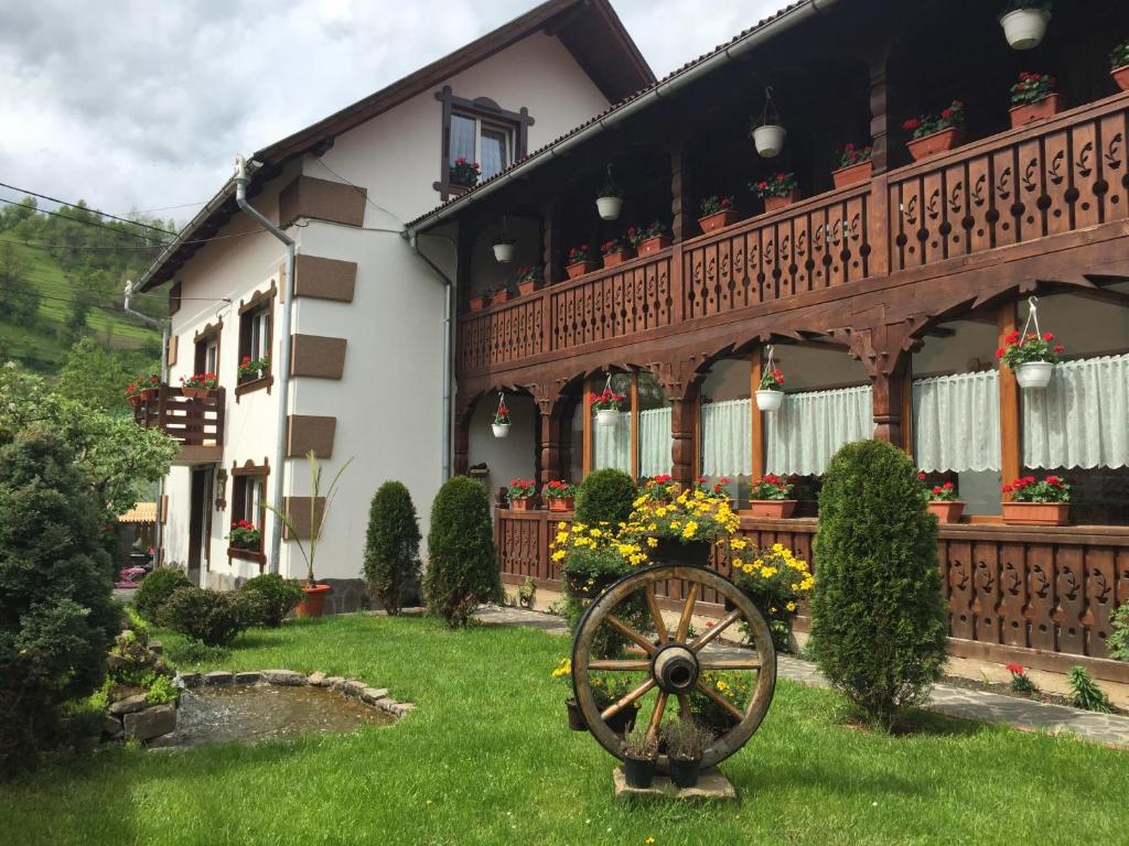 a house with a wheel in the yard at Pensiunea Cretuca in Botiza