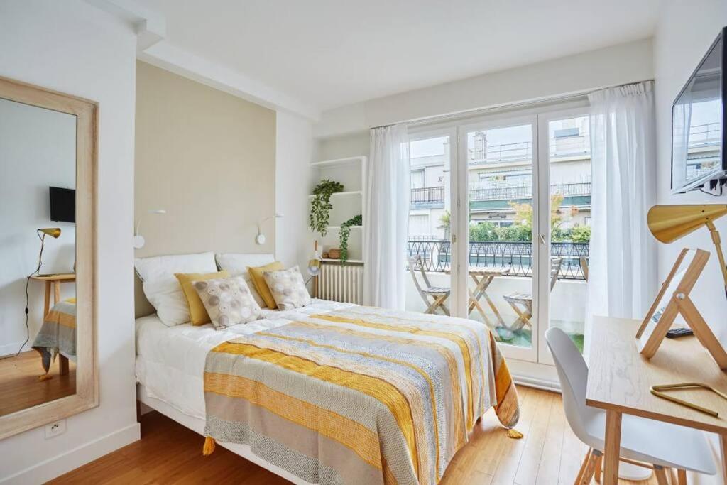 a white bedroom with a bed and a balcony at Rent a Room apartments - Degas in Paris