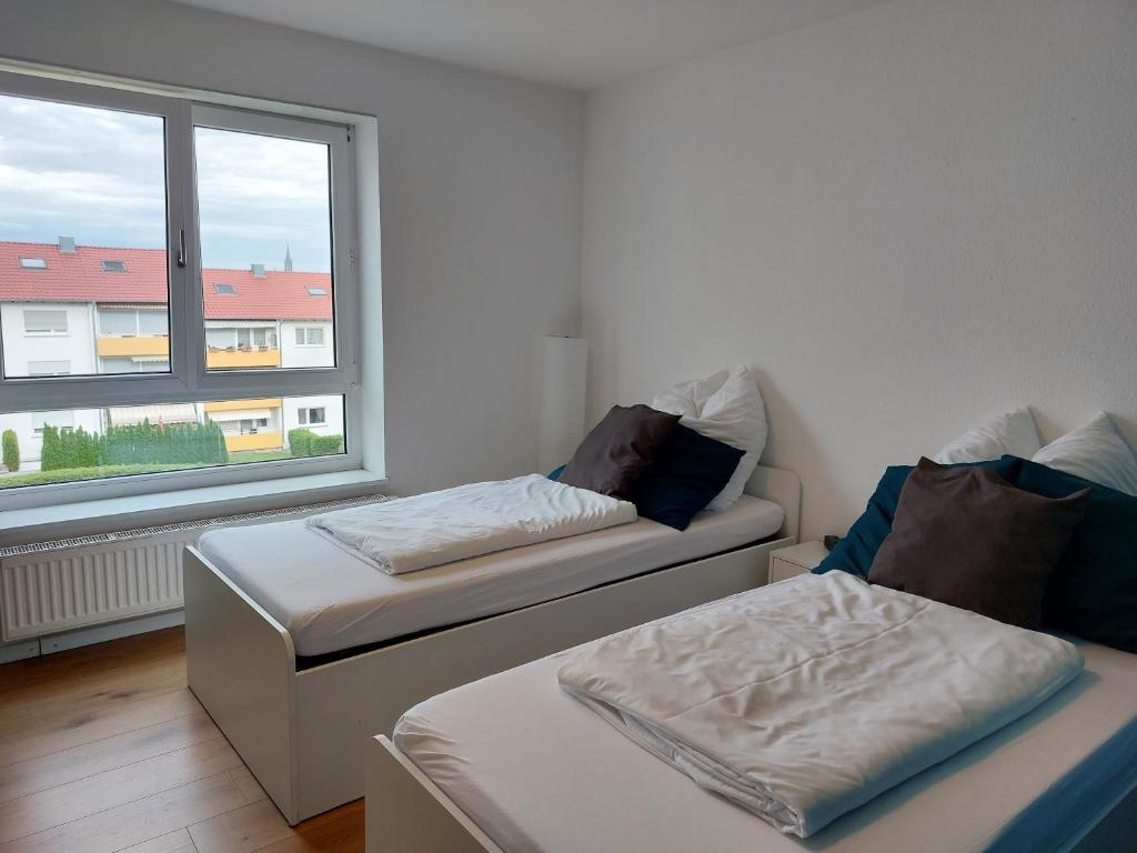 two beds in a room with a window at Rooftop Apartments - Doppelzimmer in Gemeinschaftsunterkunft (Weinberg R2) in Ulm