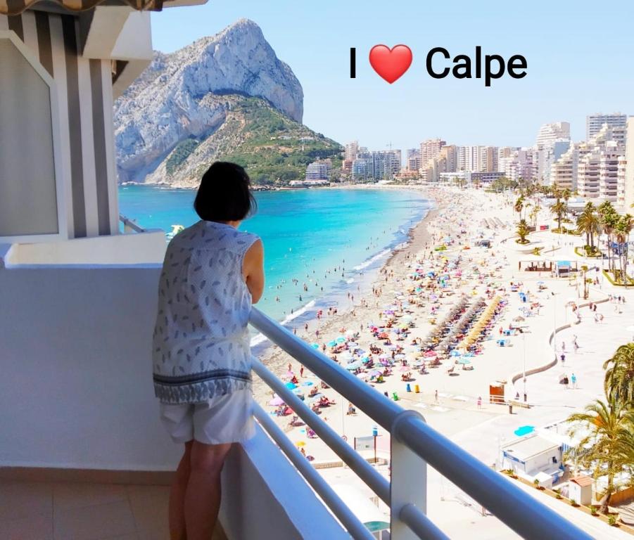 a woman standing on a balcony looking at a beach at Apartamentos Esmeralda 2 in Calpe