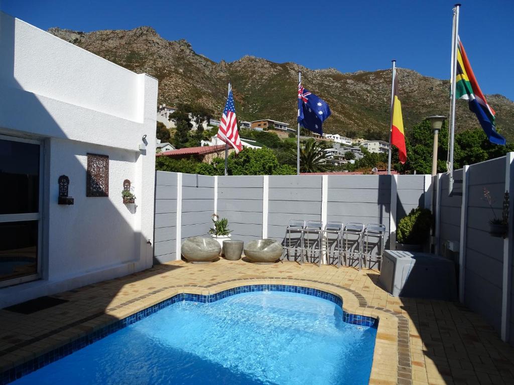 a swimming pool next to a fence with flags at Big Skies Guesthouse in Gordonʼs Bay