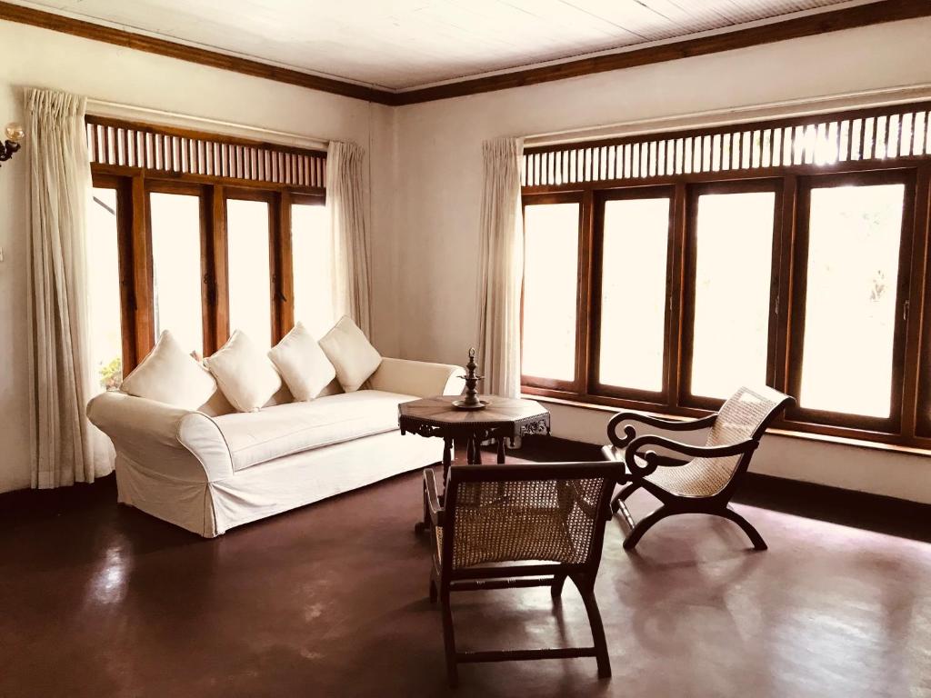 a living room with a couch and chairs and windows at Dunwatta House in Kandy