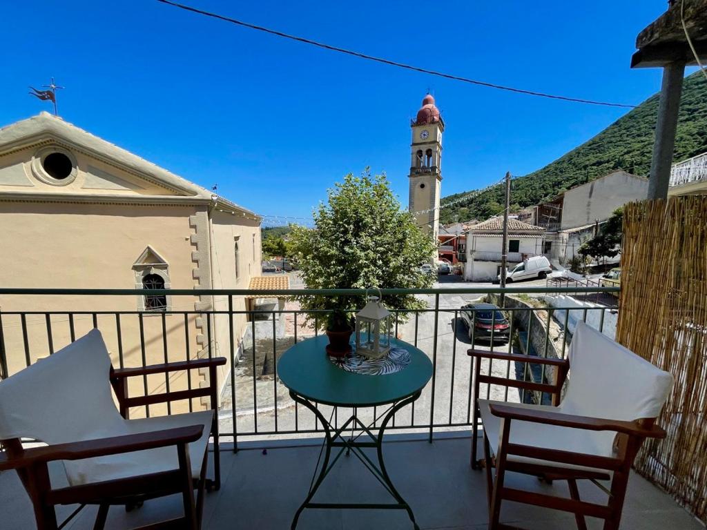 un balcone con tavolo, sedie e torre dell'orologio. di ilianas place ad Ágios Matthaíos