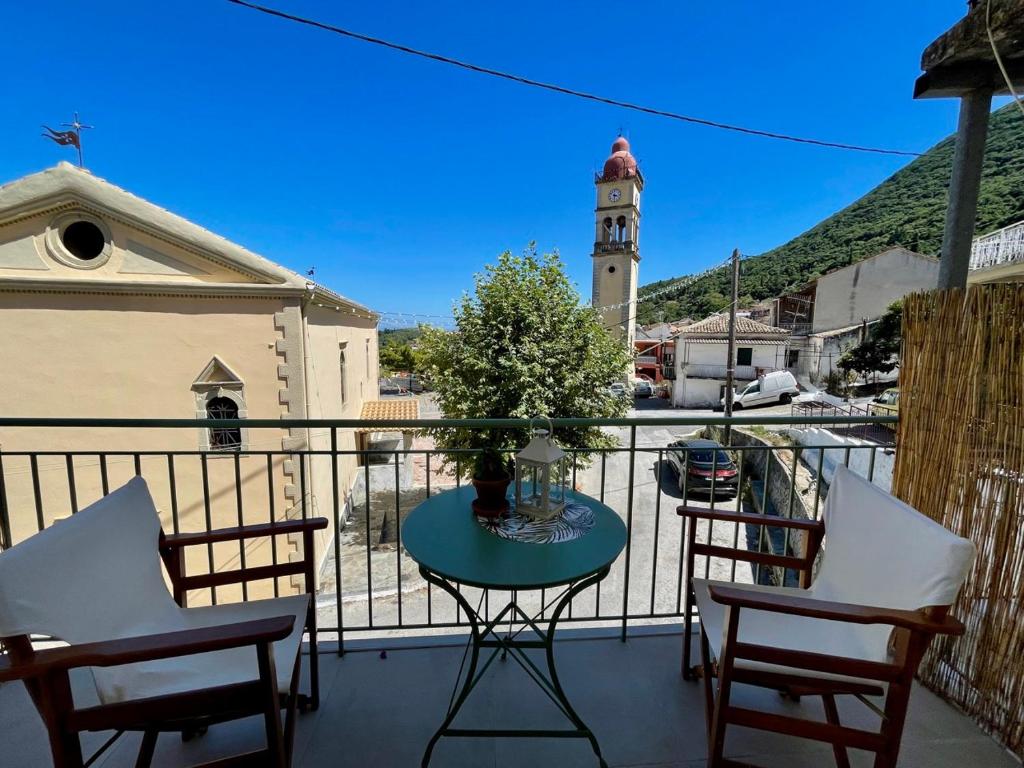 a balcony with a table and chairs and a clock tower at ilianas place in Ágios Matthaíos