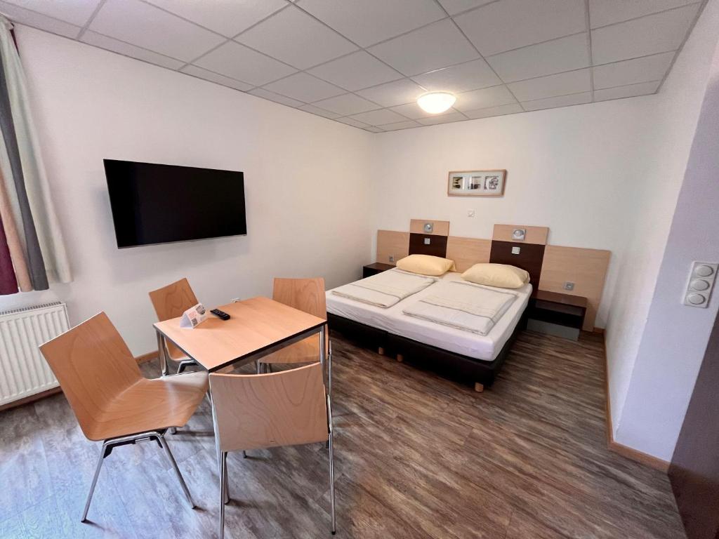 a room with a bed and a table and a tv at DJH-Gästehaus Bermuda3Eck in Bochum