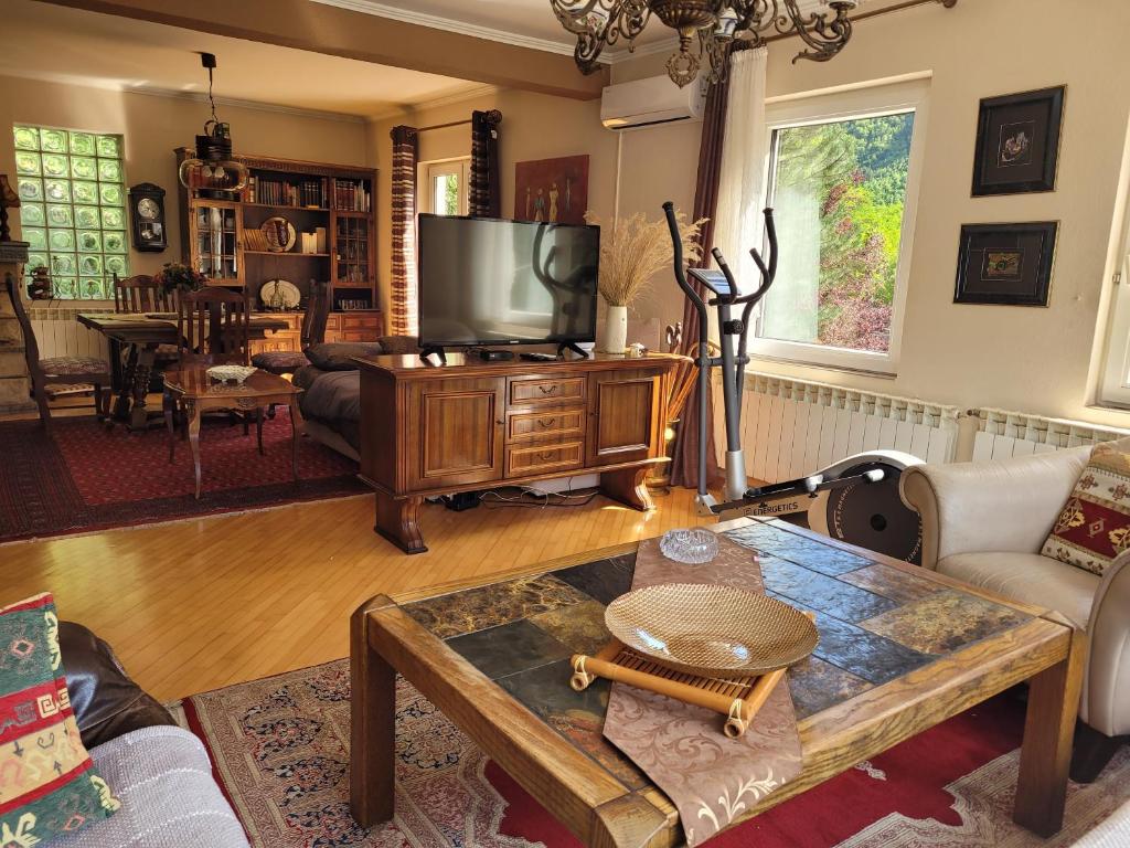 a living room with a tv and a table at Nature Guest House Sarajevo in Sarajevo
