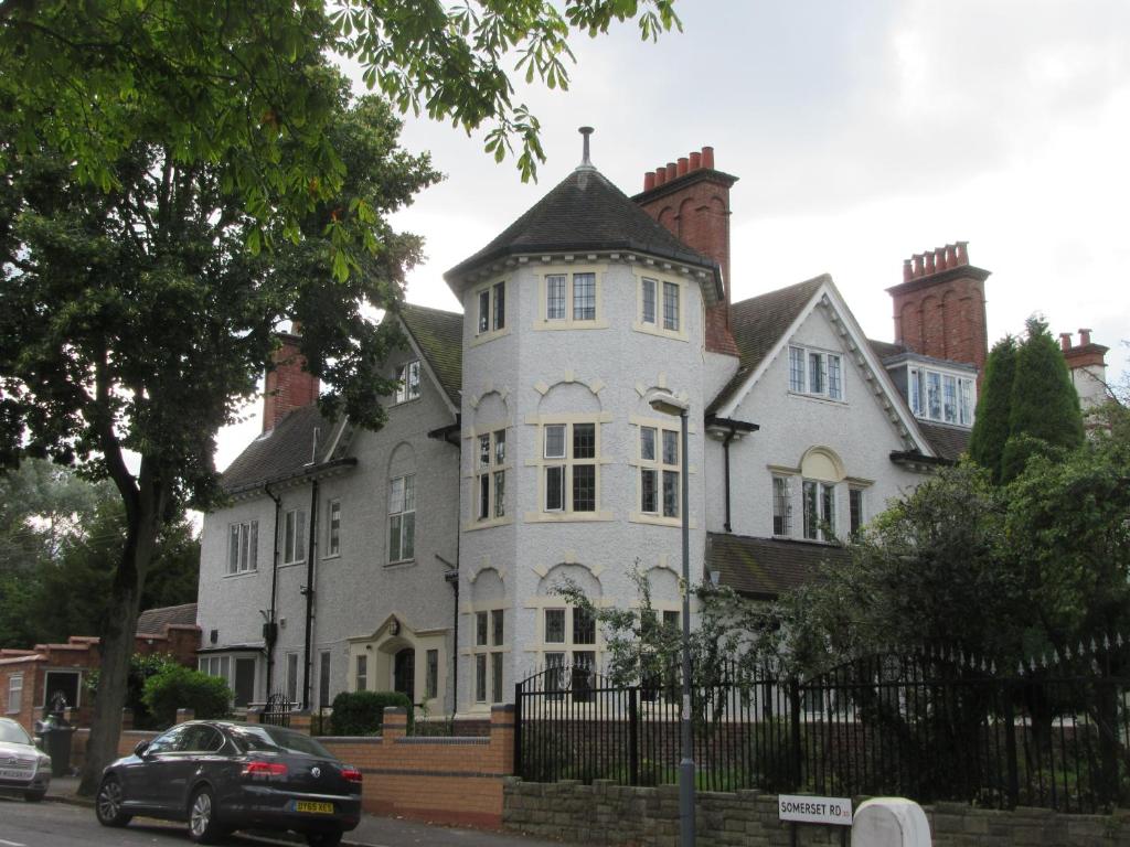 une grande maison blanche avec une voiture noire garée devant elle dans l'établissement RK Heritage House, à Birmingham