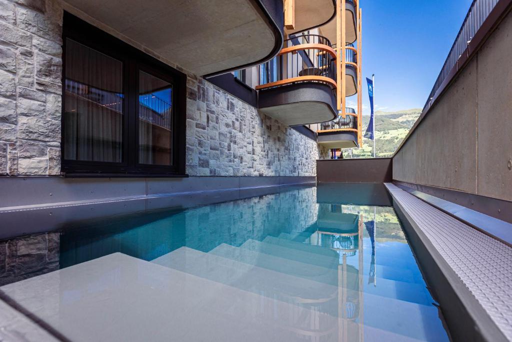 a swimming pool with a chair in a building at Zillertal Suites Fügen by ALPS RESORTS in Fügen