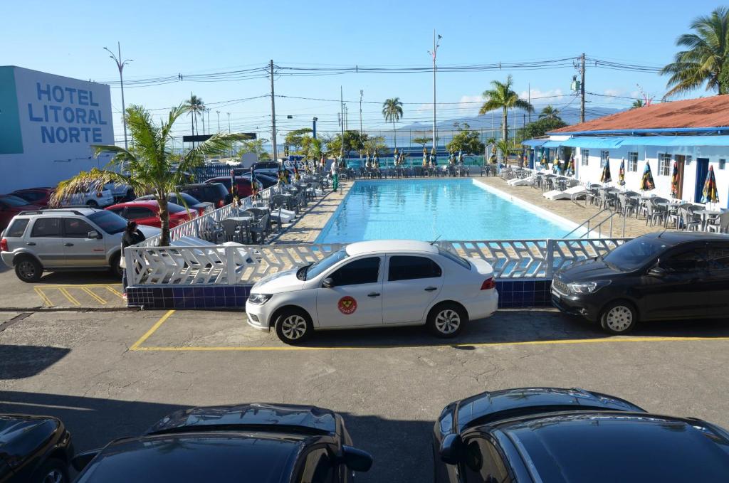 une voiture garée dans un parking à côté d'une piscine dans l'établissement Hotel Litoral Norte, à Caraguatatuba