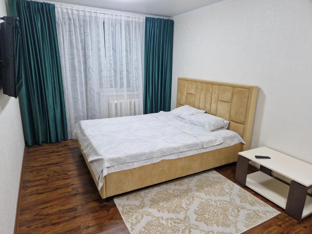 um quarto com uma cama e uma janela com cortinas verdes em Апартаменты в тихом месте em Chisinau