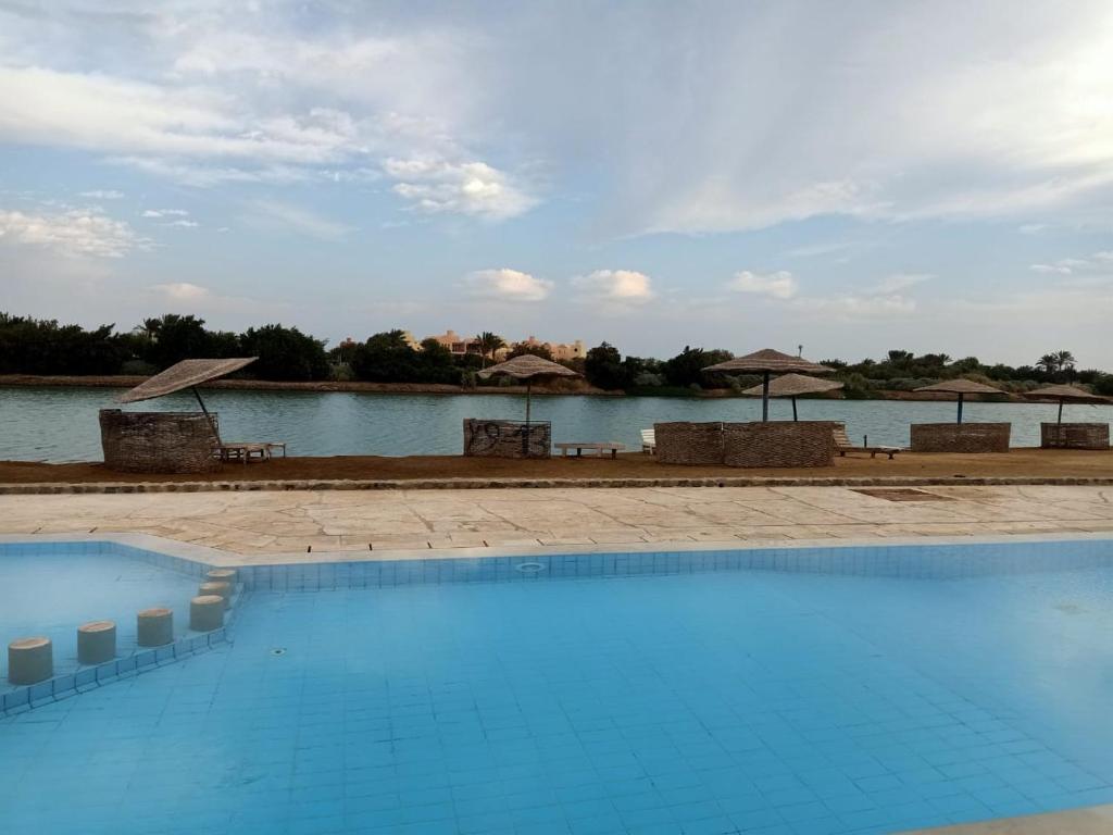 a swimming pool with umbrellas and a body of water at West golf 2bedroom in Hurghada