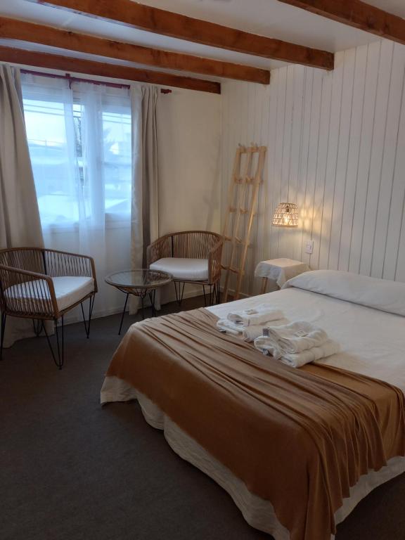 a bedroom with a bed with two chairs and a table at Los Calafates Hotel in Ushuaia