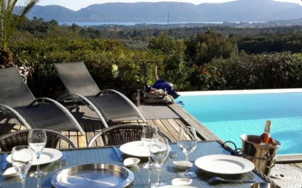 - une table avec des verres et des assiettes à côté de la piscine dans l'établissement Villa ANCHORAGE vue mer panoramique, à Porto-Vecchio