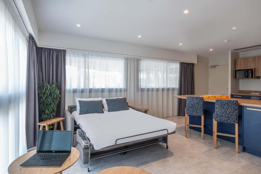 a bedroom with a bed and a laptop on it at L'Escale Marine, The Originals Relais in Crozon