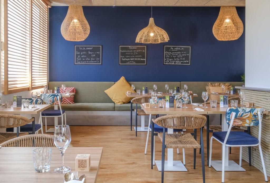 a restaurant with tables and chairs and a couch at L'Escale Marine, The Originals Relais in Crozon