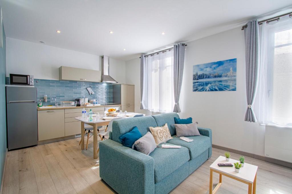 sala de estar con sofá azul y cocina en Cocon d'Hiver - Netflix & Wifi - Parking Gratuit - check-in 24H24 - Kit Bébé Inclus, en Châlons-en-Champagne