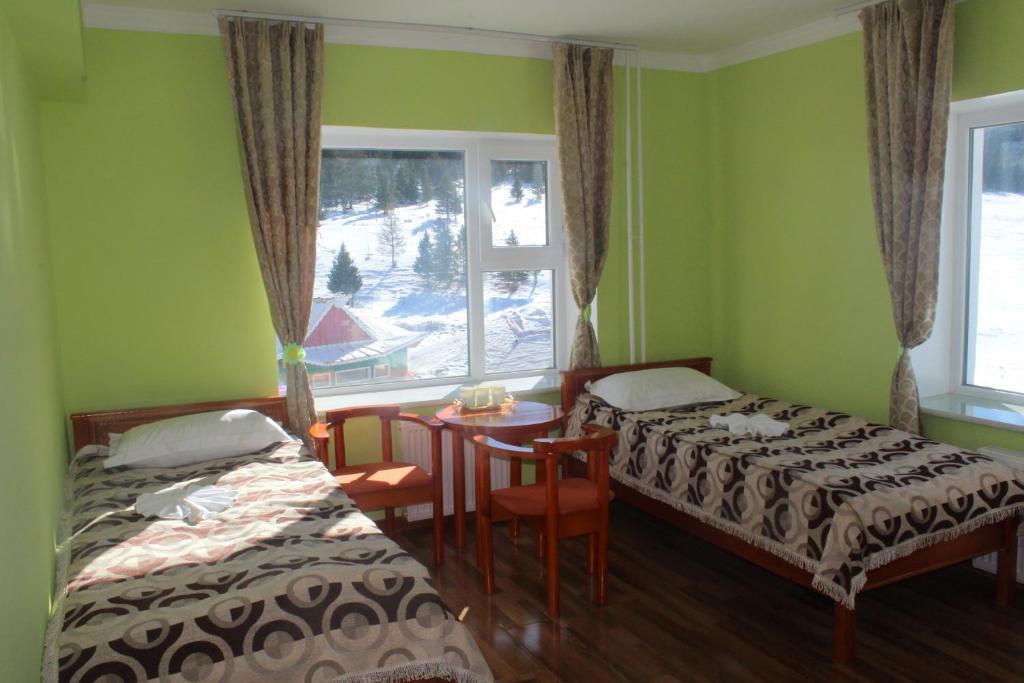 a bedroom with two beds and a table and a window at Sara's Camp in Dzuunmod